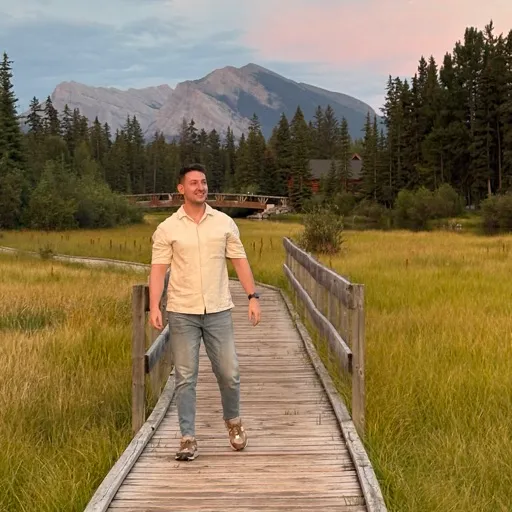 Paul, Orbilu's founder, walking along a wooden boardwalk with mountains behind